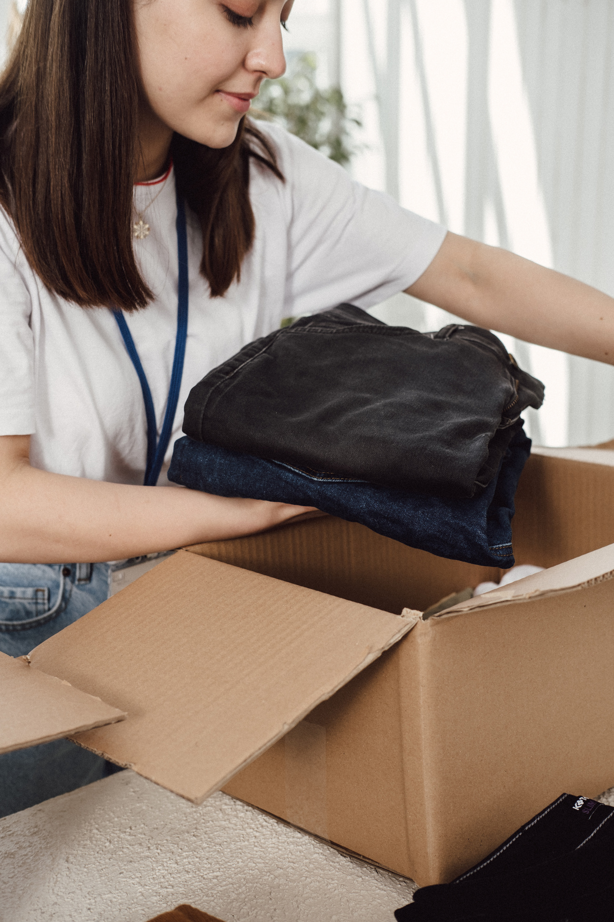 Woman Arranging Box of Clothing Donations